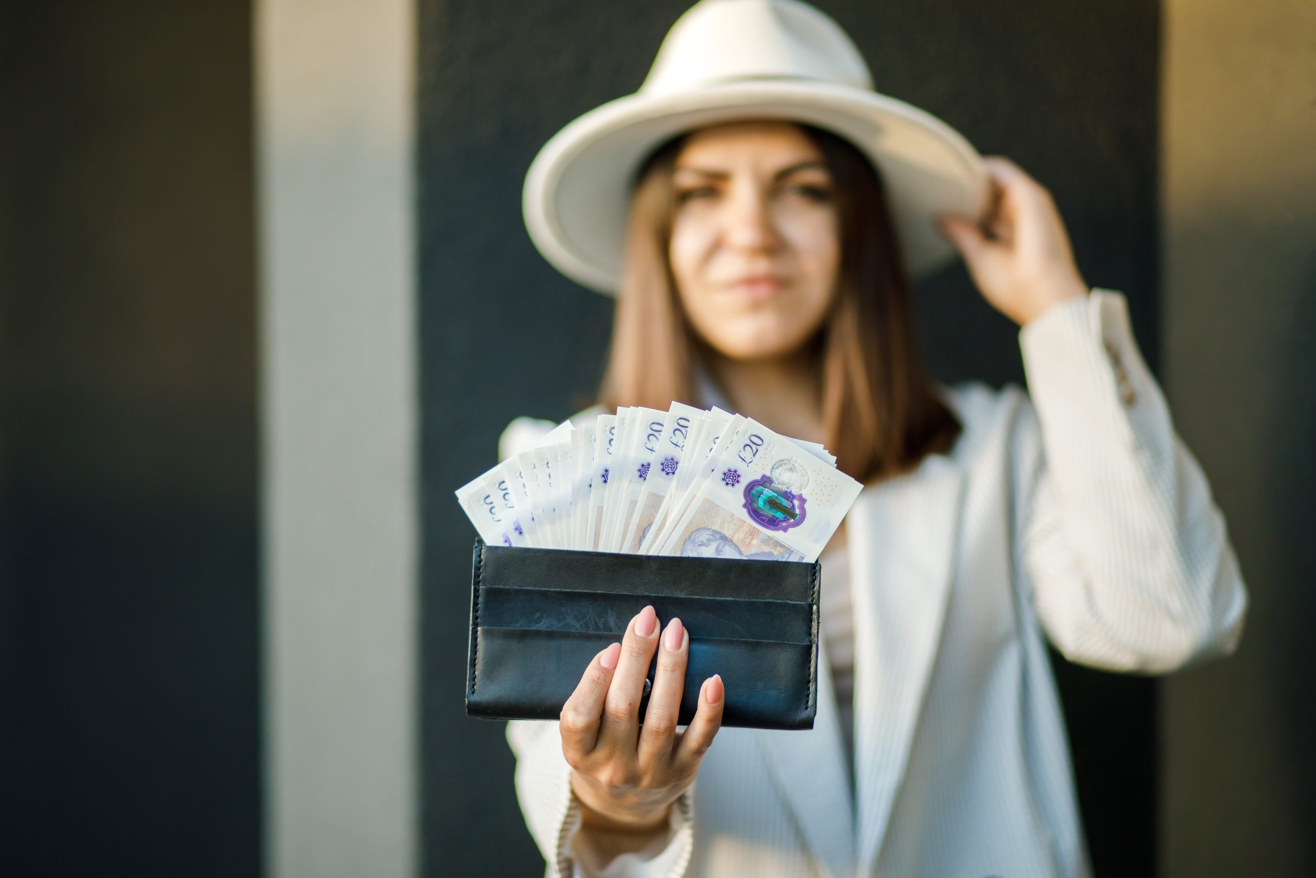 Young,Business,Woman,Holding,Black,Wallet,With,Pounds,In,Hands,