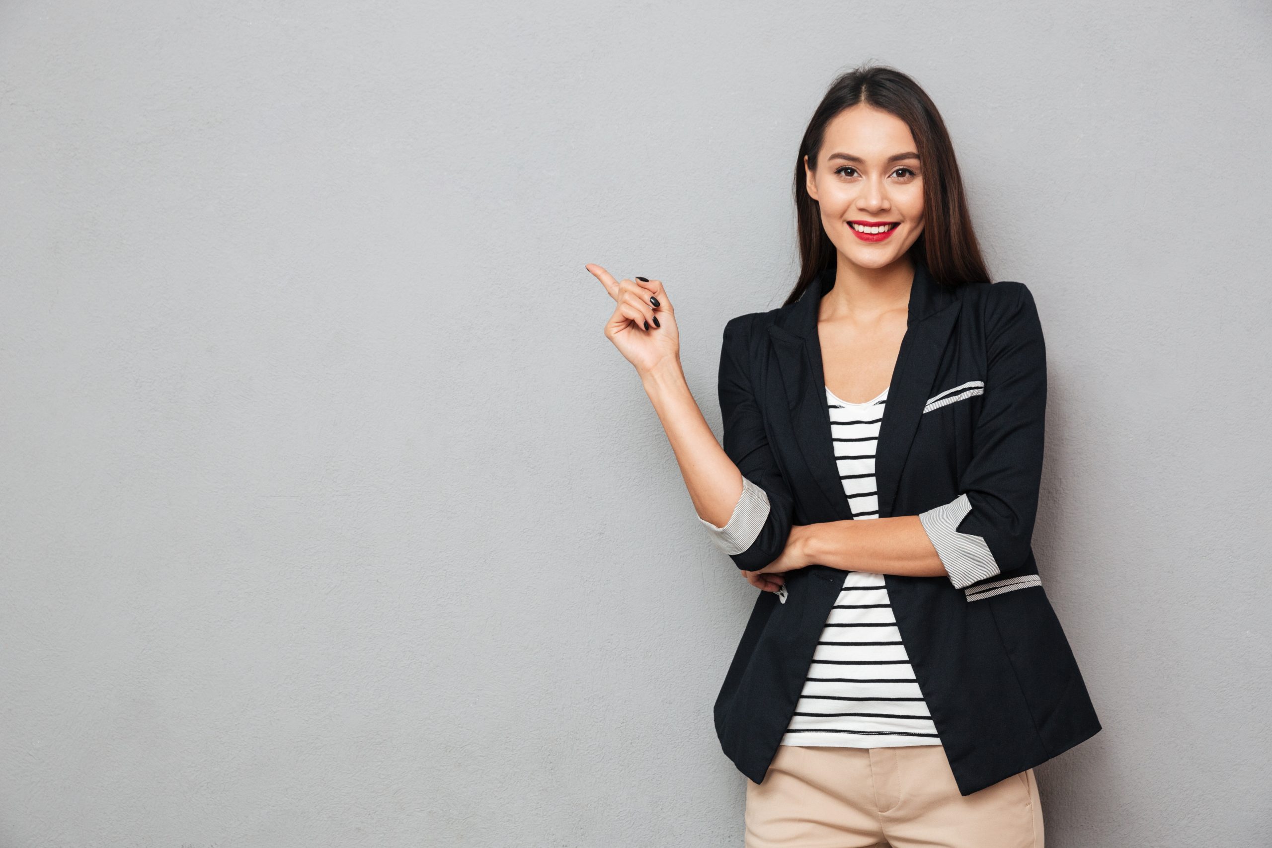 Smiling,Asian,Business,Woman,Pointing,Up,And,Looking,At,The